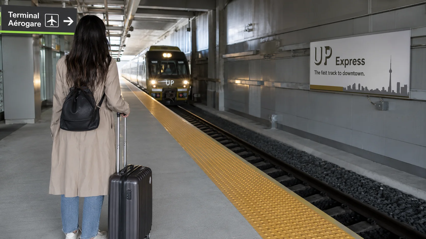 UP Expressのホームでスーツケースを持って待つイメージ